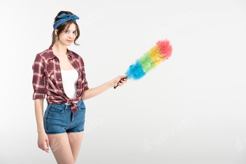 Preview: Beautiful young housewife holding colorful duster isolated on white