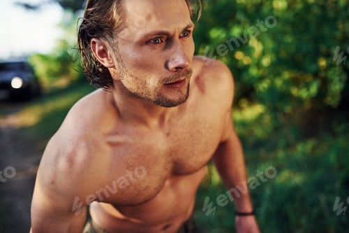 Preview: Close up portrait. Handsome shirtless man with muscular body type is in the forest at daytime