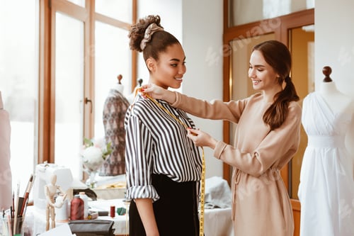 Preview: Young fashion designer taking measurements for african model