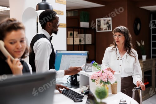 Preview: Hotel staff helping woman with check-in