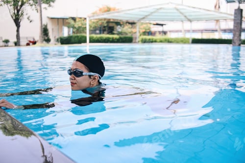 Preview: Cheerful Asian Young Female Swimming On The Side Of Pool