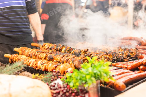 Preview: vendor fries meat and sausage on the grill in the city center at the Christmas market