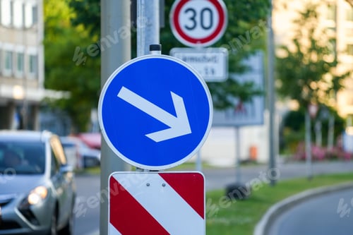 Preview: Closeup shot of a blue circular traffic sign with an arrow pointing down and a blur background