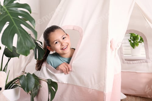 Preview: Cute little girl peeking out window of toy wigwam at home