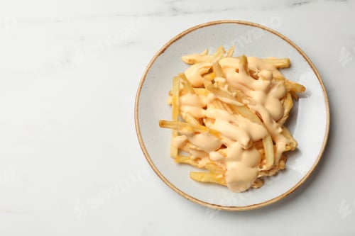 Preview: Delicious French fries with cheese sauce on white marble table, top view. Space for text