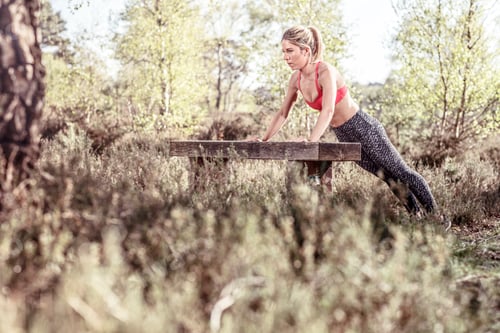 Preview: Young woman in rural setting, exercising, doing push-ups on bench