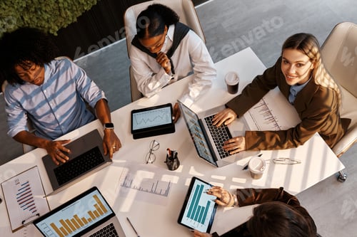 Preview: Diverse business team analyzing charts during office meeting from top view
