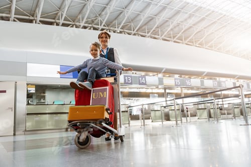Preview: Female airport worker pushes a little boy on a baggage cart through the airport terminal