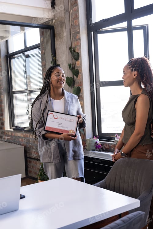 Preview: Smiling colleagues celebrating achievement with certificate in modern office setting