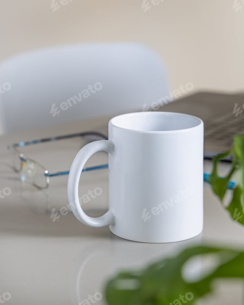 Preview: White coffee mug on grey office table against laptop, glasses and plant closeup, mockup