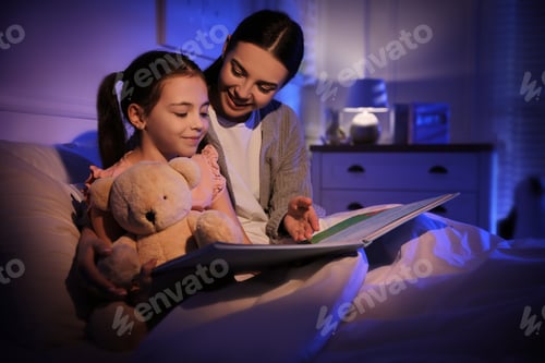 Preview: Mother with little daughter reading fairy tale in dark bedroom