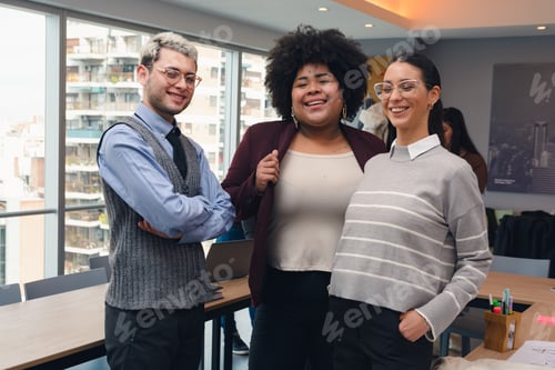 Preview: Two Women and a man, business people, are standing in the office, smiling and posing for a photo