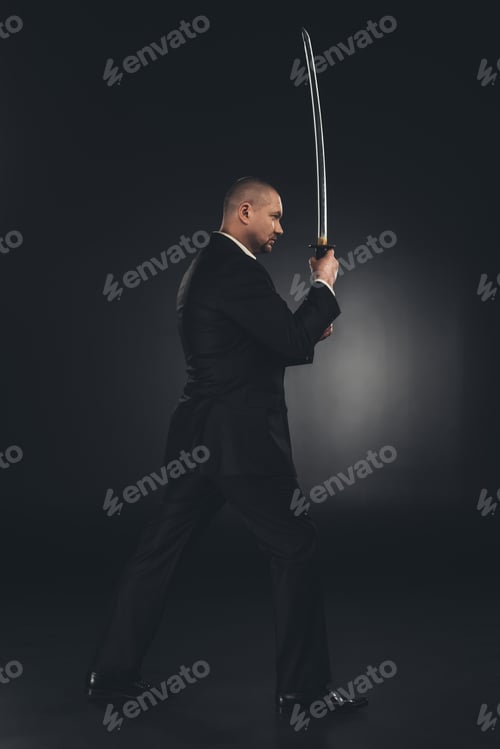 Preview: side view of yakuza member in suit with katana sword on black