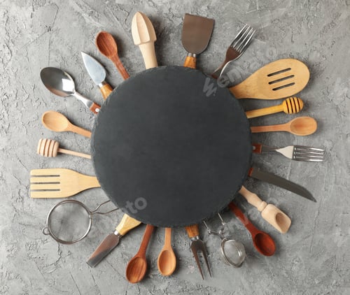 Preview: Composition with different kitchen cutlery and round cutting board on gray background