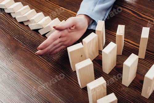 Preview: partial view of woman preventing wooden blocks from falling at desk