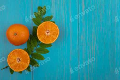Preview: top view copy space orange with halves and branch of leaves on turquoise background