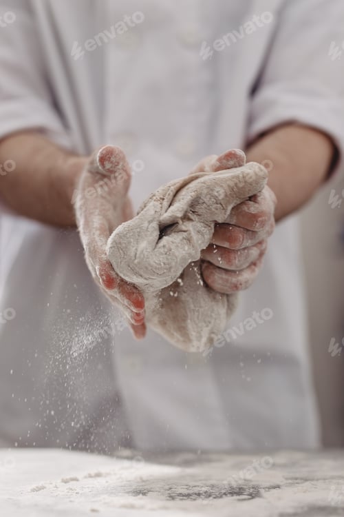Preview: Professional baker kneads dough in his hands in the kitchen of the bakery