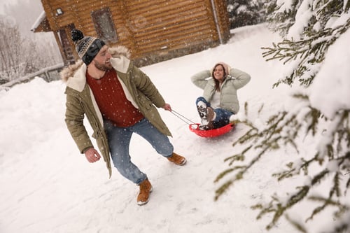Preview: Young man pulling sled with his girlfriend outdoors on snowy day. Winter vacation