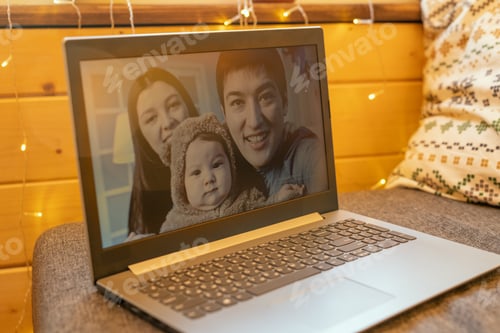 Preview: Happy young family of three on display of laptop standing on large soft sofa