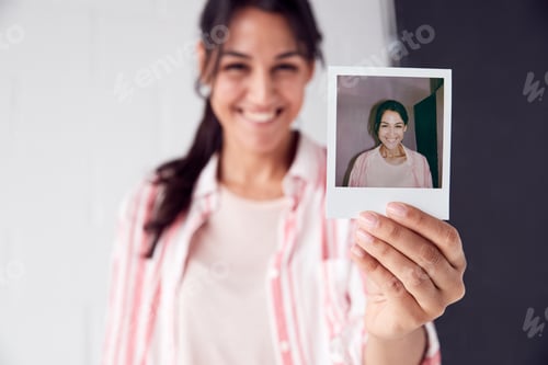 Preview: Portrait Of Female Photographer On Photo Shoot Holding Up Instant Polaroid Print In Studio