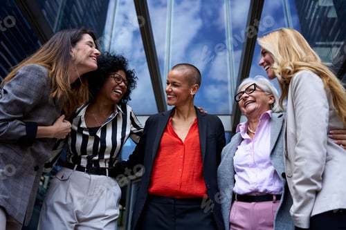 Preview: Low angle of team of diverse business women laughing together happy at entrance of modern