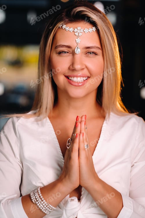 Preview: Portrait of a smiling girl in a white dress with her palms clasped in front of her