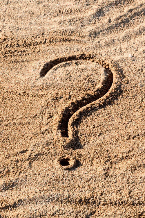 Preview: question marks written on beach sand close up, with copy space