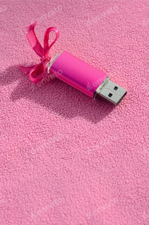 Preview: Brilliant pink usb flash memory card with a pink bow lies on a blanket of soft and furry light pink