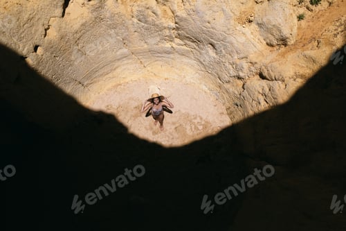 Preview: woman standing in rocky cave with hole in summer