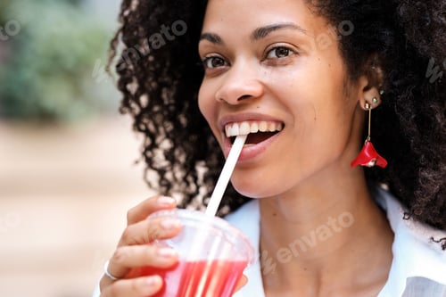 Preview: Happy black woman drinking a strawberry juice..