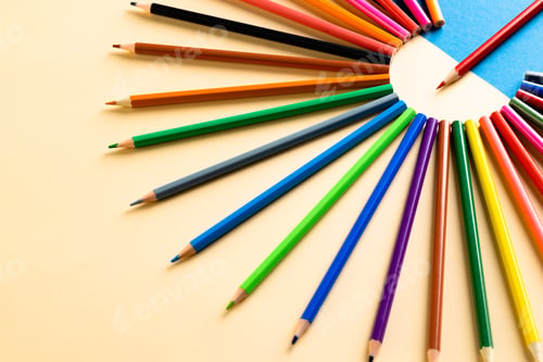 Preview: Close up of multi coloured pencils in circle and copy space on blue and yellow background