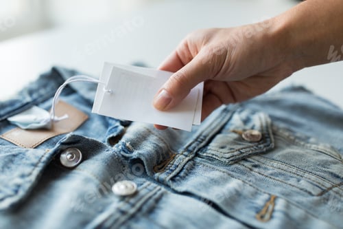 Preview: close up of hand holding price tag of denim jacket