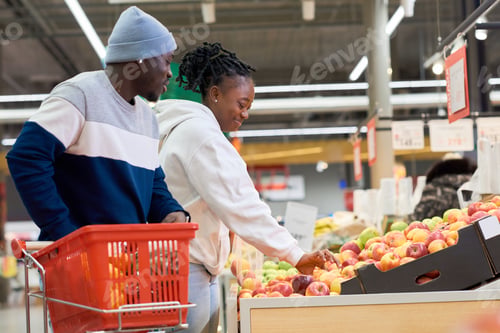 Preview: Side view of young woman taking red apple and putting it into cellophane bag