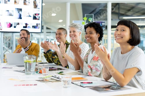 Preview: Diverse business people clapping hands while sitting in the meeting