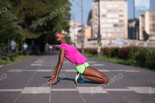 Preview: sporty young african american woman stretching outdoors