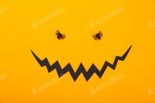 Preview: Decorative spiders and paper mouth on yellow background, top view