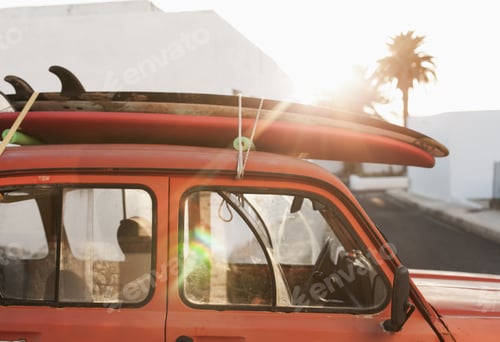 Preview: A stack of surfboards on a retro car roof with sun shining. Summer and surf background wallpaper.