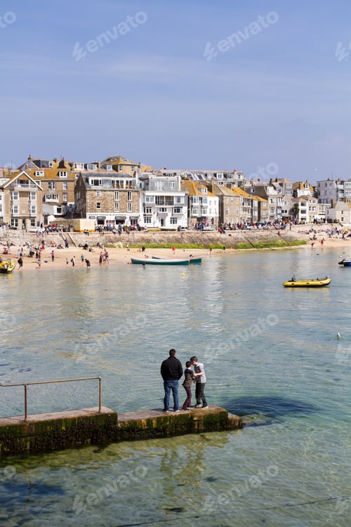 Preview: A father and his sons standing on the jetty in the middle of St Ives harbour in Cornwall UK
