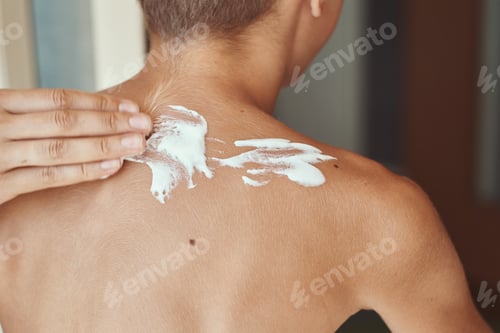 Preview: Mother applying sunscreen cream on son shoulders. Summer holidays and vacation concept