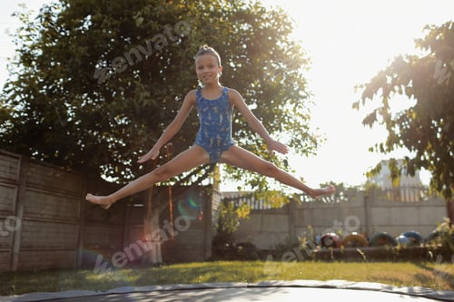 Preview: little sports girl jumps on a trampoline. Outdoor shot of girl jumping on trampoline, enjoys jumping