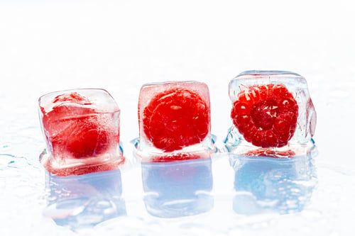 Preview: Frozen berries in ice cubes on pink