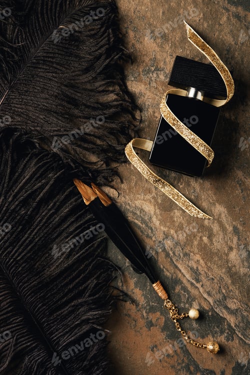 Preview: top view of perfume bottle with golden ribbon and decorative black feathers