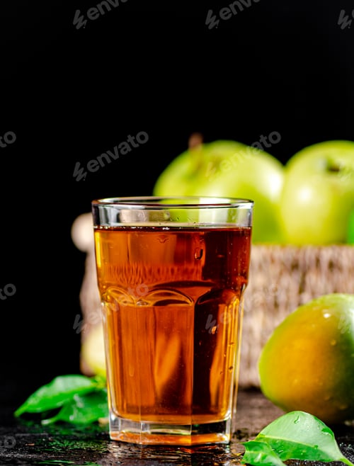 Preview: A glass of green apple juice with leaves on the table.