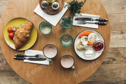 Preview: top view of empty teacups, sandwich and cheesecakes on table served for breakfast