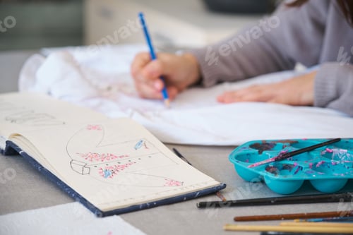 Preview: Unrecognizable woman painting a design in a white shirt.