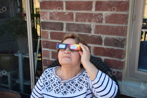 Preview: Senior woman watching solar eclipse using special eye glasses