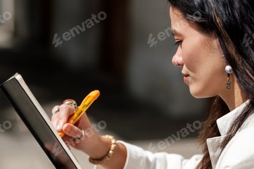 Preview: Close side view of woman writing on diary.