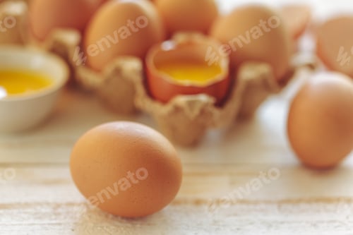 Preview: Fresh eggs and cracked shells placed on wooden table for cooking