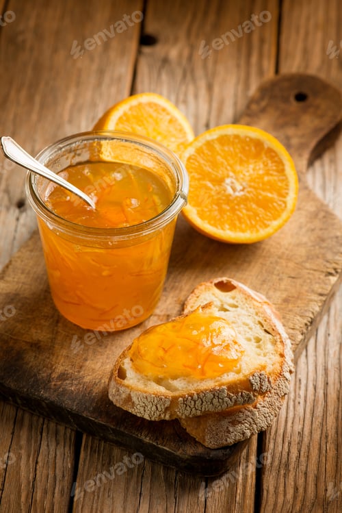 Preview: orange marmalade with bread over wooden background