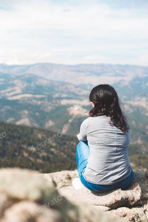 Preview: Woman relaxing and meditating at the top of the mountains enjoying nature